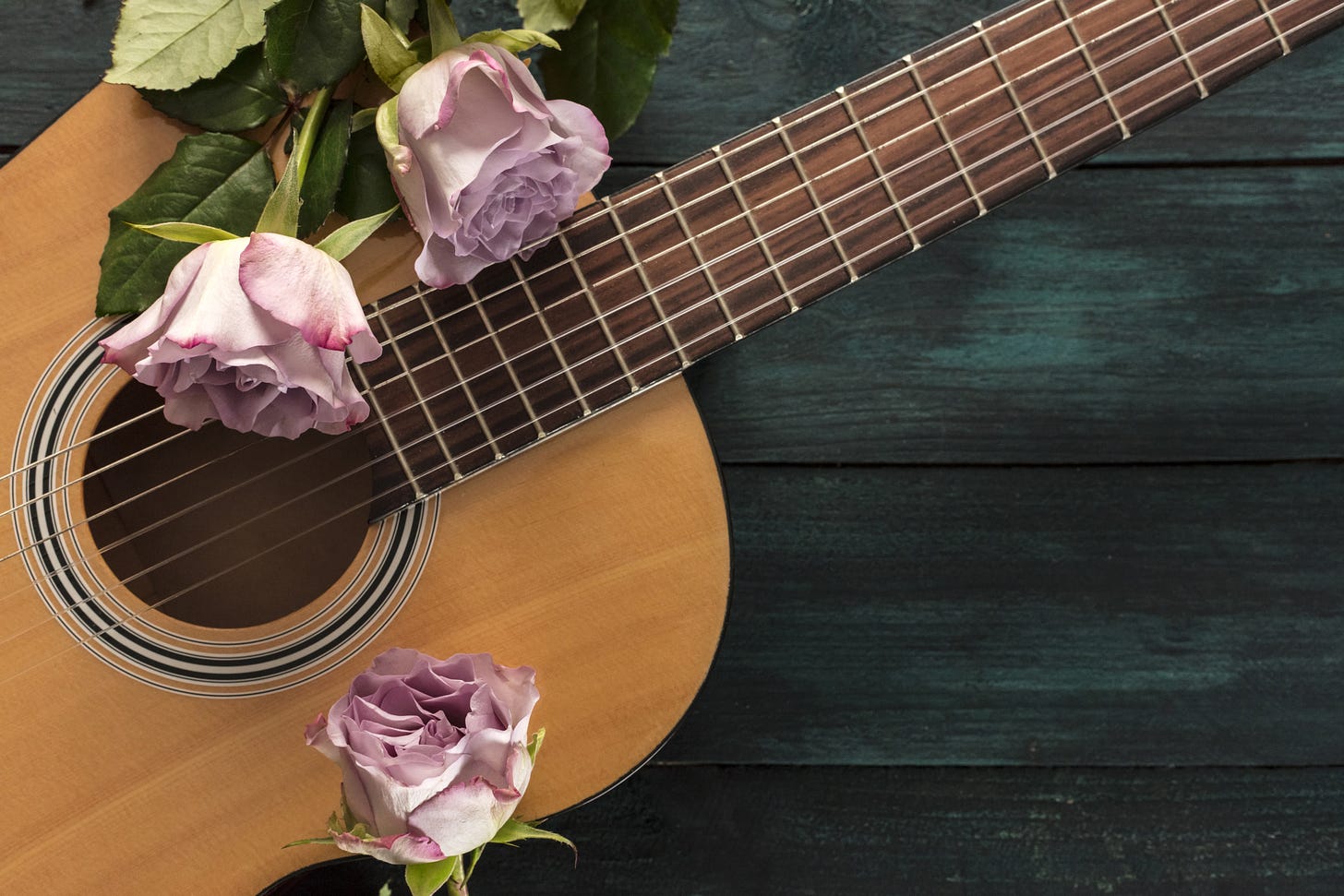 Image of a guitar on a wooden floor with pink roses