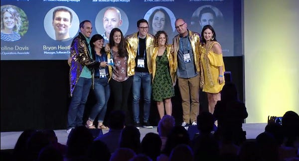 a group of adults standing on stage holding a LinkedIn award in front of a large crowd
