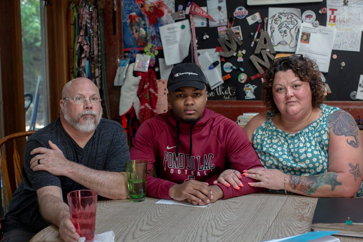 Amy and Dan Wempner, both white, sit on either side of their 18-year-old son Armond, who is Black, at a kitchen table.