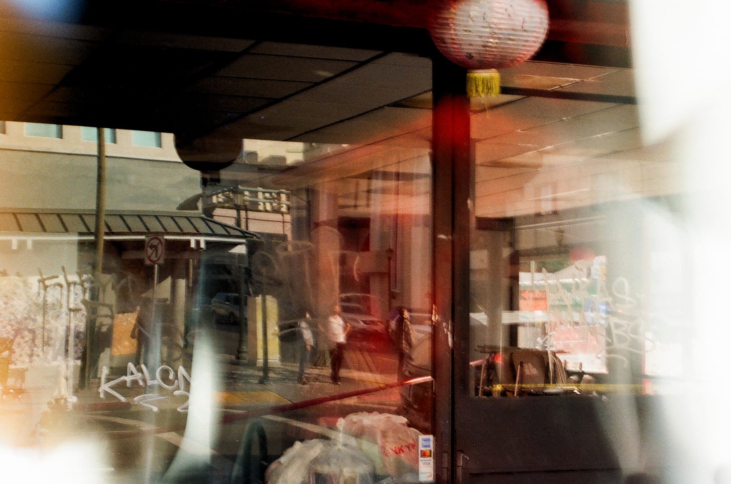 Colorful photo of Oakland Chinatown's storefront with people reflected in window.