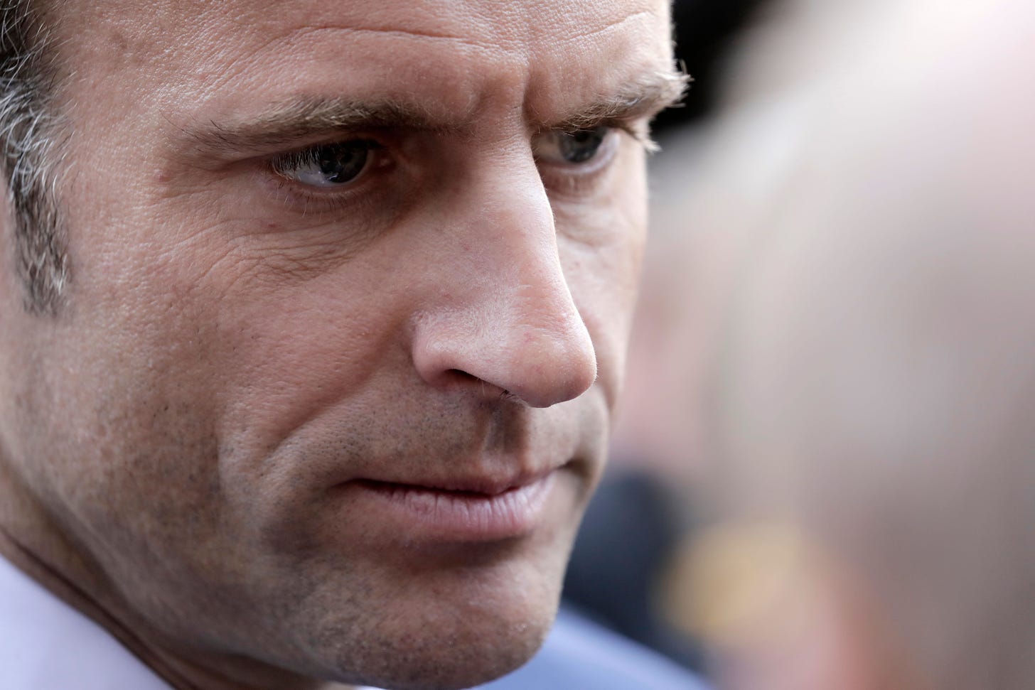 France's President and Republique en Marche (LREM) candidate for re-election Emmanuel Macron looks on as he speaks with onlookers while campaigning in Denain, northern France on April 11, 2022