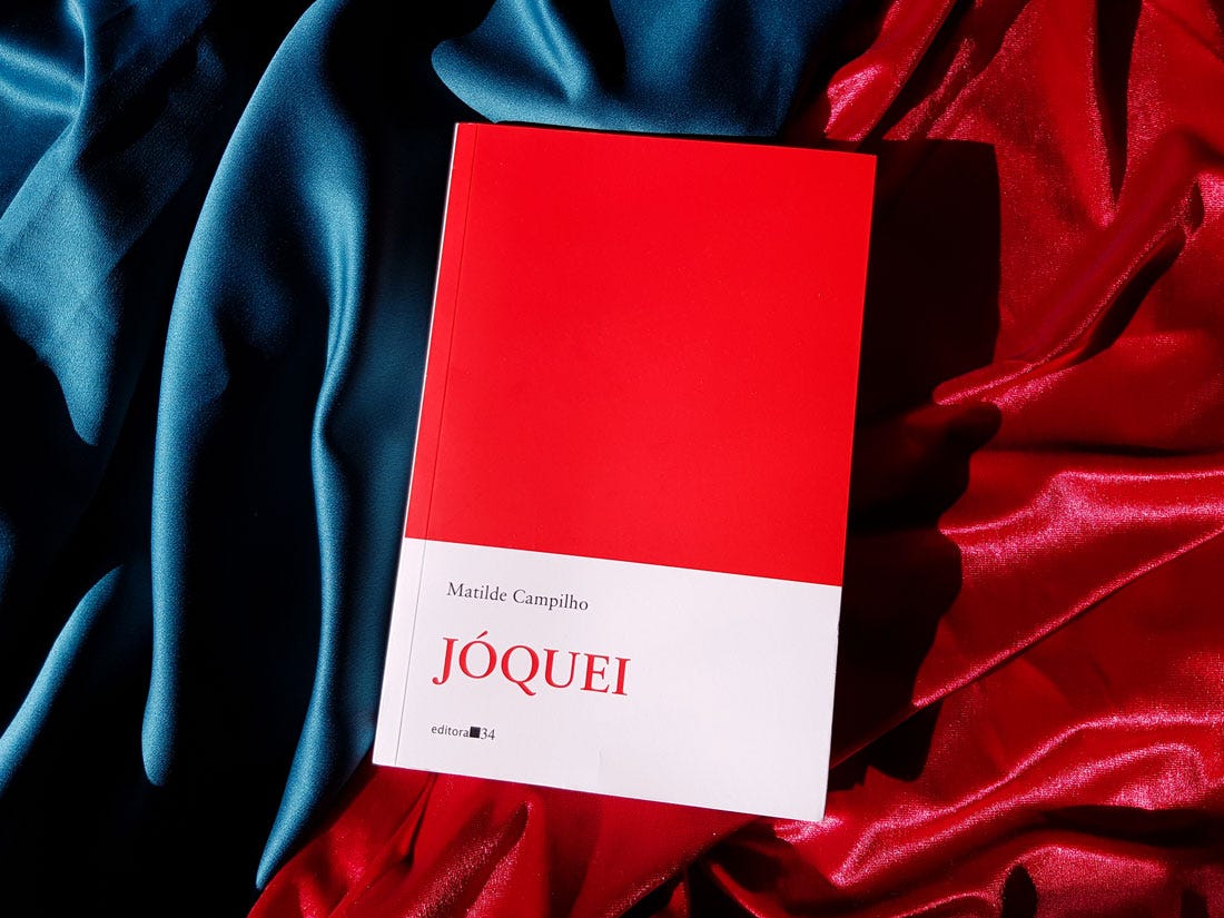 Foto da capa do livro Jóquei de Matilde Campilho, sobre tecidos vermelho e verde. A capa tem um grande quadrado vermelho na parte de cima, com a parte de baixo em branco para o nome da autora, título e logo da editora 34.