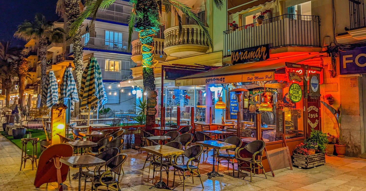 A very colorful cafe at night on the boardwalk of Sitges. All the tables are empty because of the rain. 
