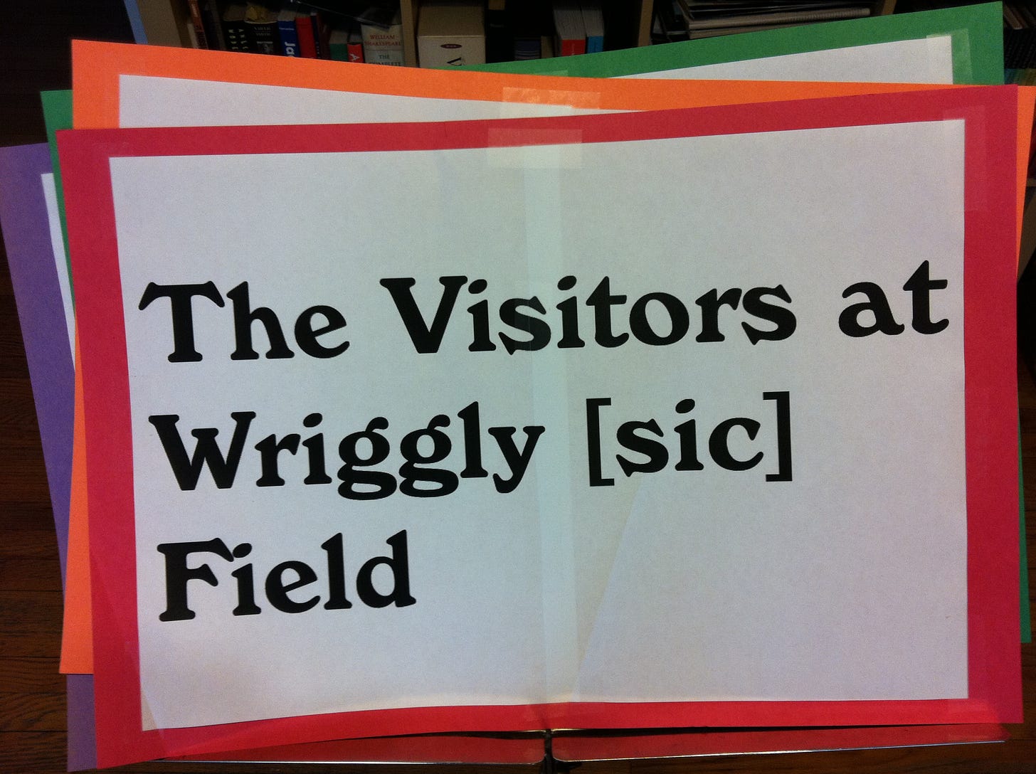 A sign mounted on red construction paper reads: "The Visitors at Wriggly [sic] Field"