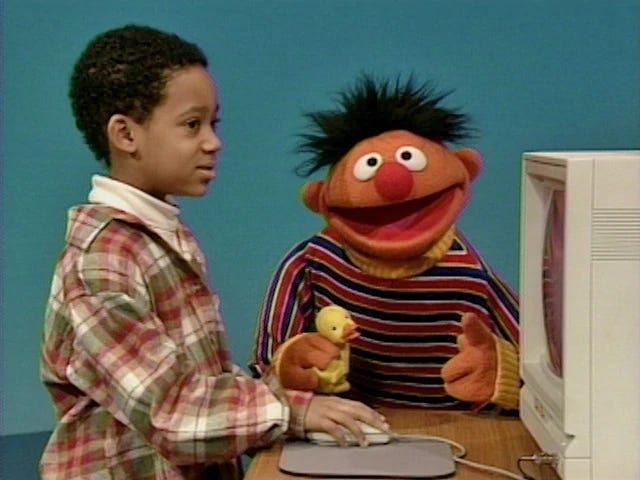 Tyler and Ernie and a rubber duckie sit before a computer perhaps in the early 90s? they are projecting together