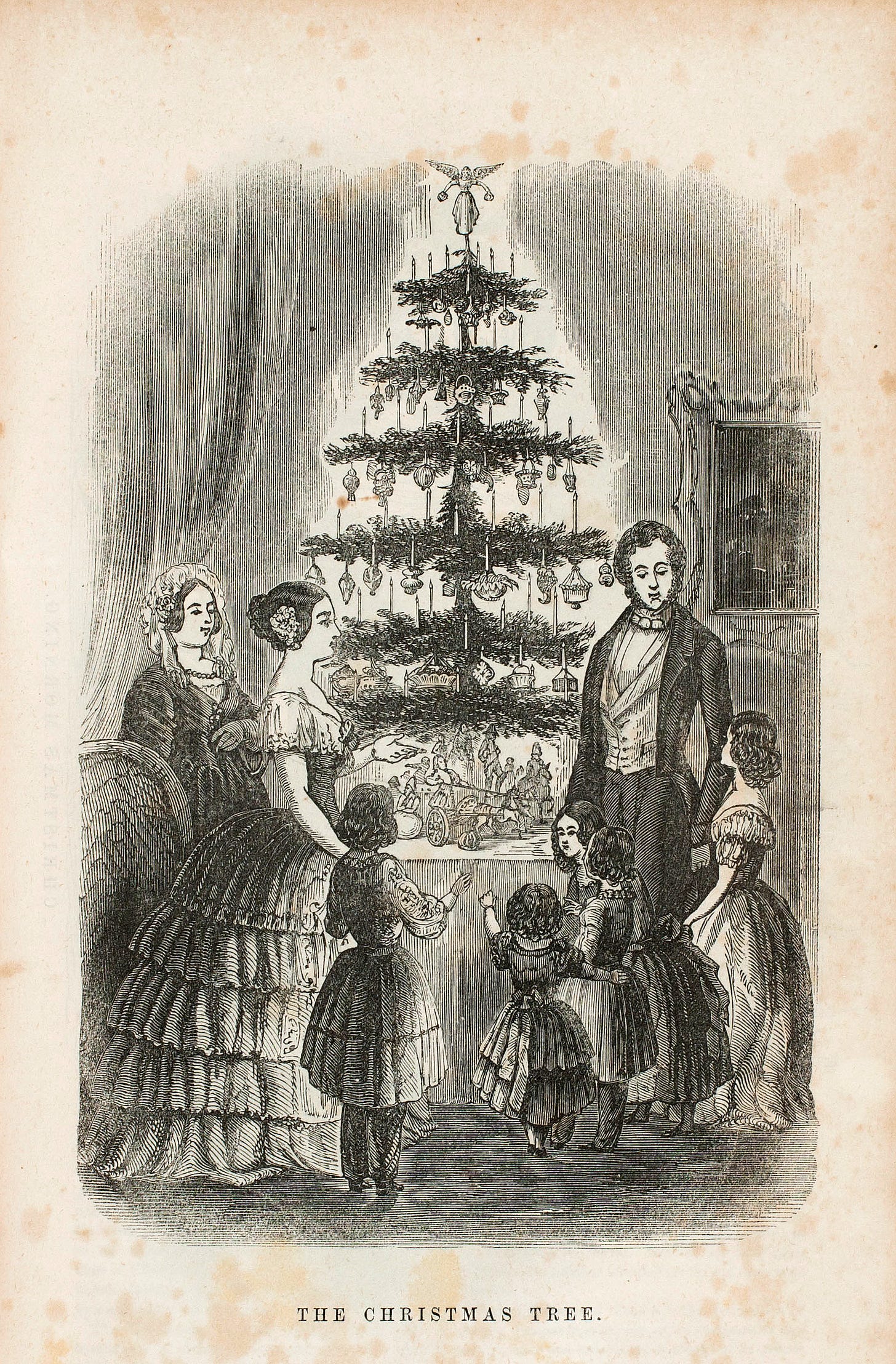 black-and-white engraving of Victorian family in front of tabletop Christmas tree. Tree is decorated with dangling ornaments and topped with an angel. Family 