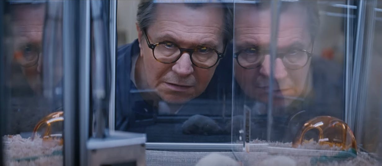 From the film "Crisis": Gary Oldman, playing a scientist with glasses, stares concerned into a glass cage with experimented on mice.