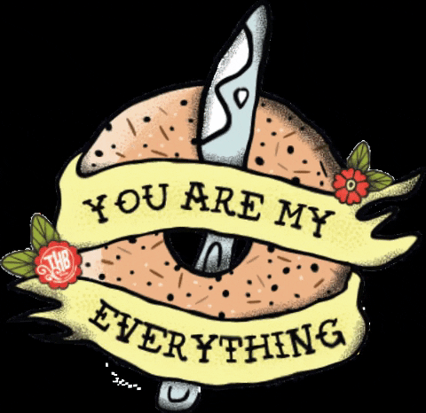 An everything bagel with the words "You are my everything" on it with a cream cheese knife through its center.