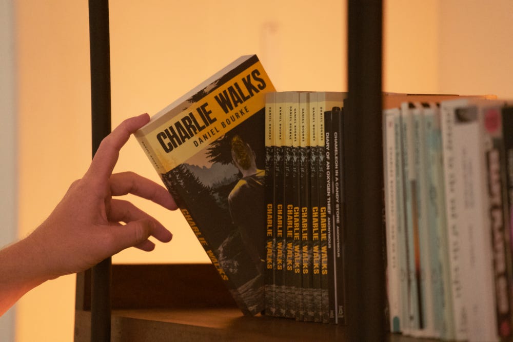 A book being pulled out of a bookshelf with the title Charlie Walks and author Daniel Bourke