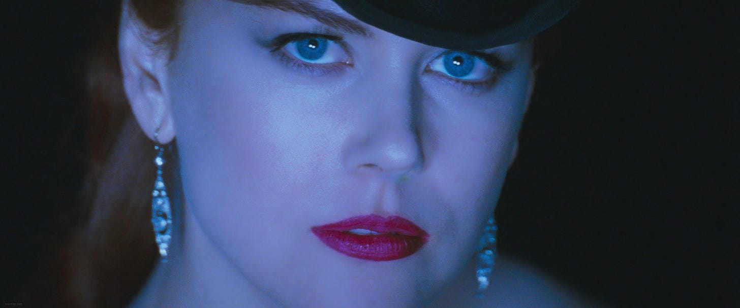 Film still from Moulin Rouge. Nicole Kidman looks intensely into the camera, with red lipstick and beautiful diamond earrings.