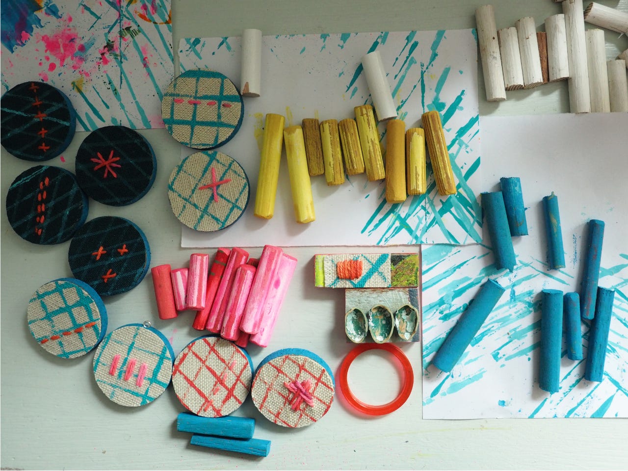 colourful components for brooches and other accessories arranged on a desk, viewed from above.