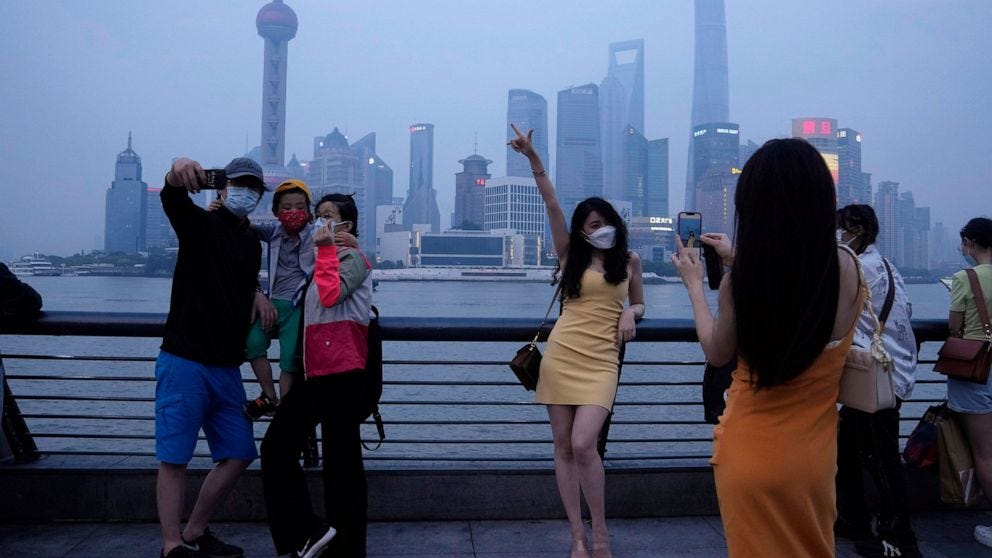 Residents pose for photos along the bund, Wednesday, June 1, 2022, in Shanghai. Traffic, pedestrians and joggers reappeared on the streets of Shanghai on Wednesday as China's largest city began returning to normalcy amid the easing of a strict two-mo