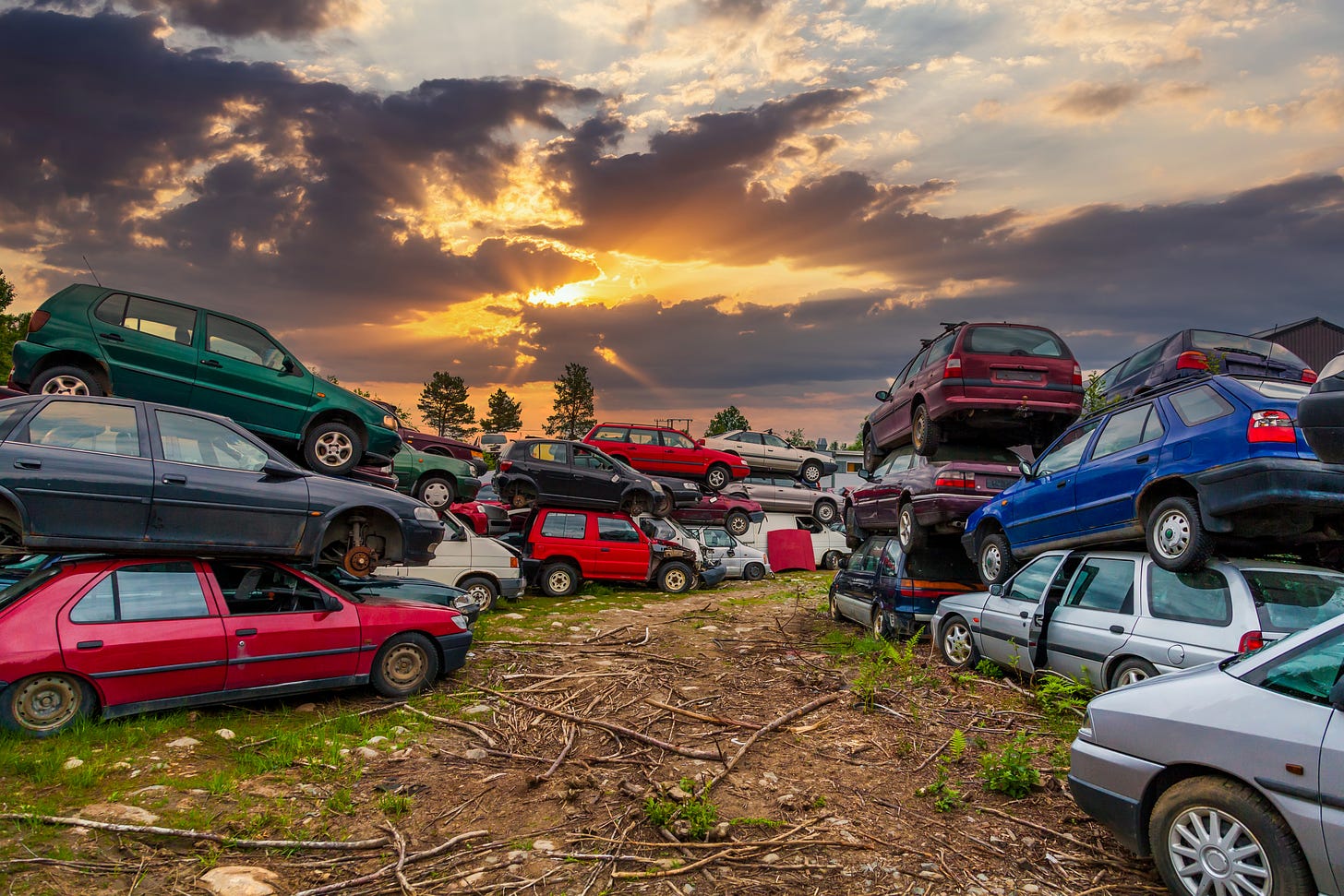 Cars piled ina junkard at sunset