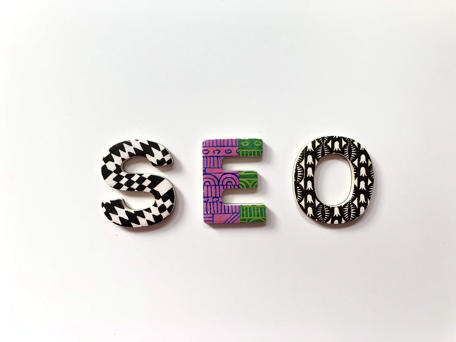 "SEO" written in colorful embroidery on a plain white backdrop