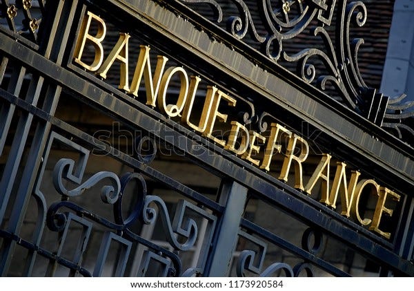 Besançon, France - February 17, 2008: Low angle view of the wrought iron gate of the Bank of France building with the golden letters of the signboard lit by the sun.