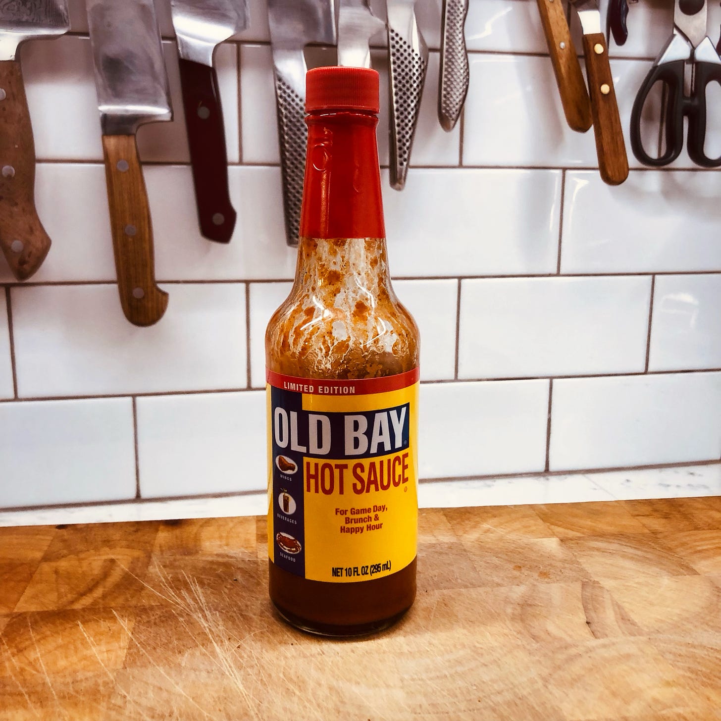 A half-empty bottle of Old Bay hot sauce on a cutting board in a kitchen