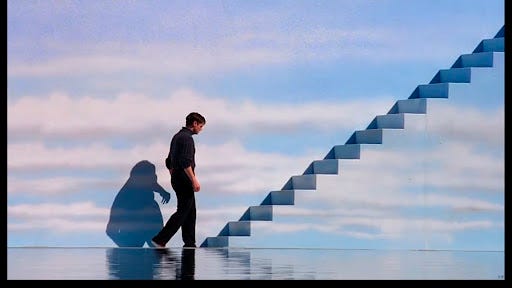 Truman standing near cloud-covered stairs in Truman Show.