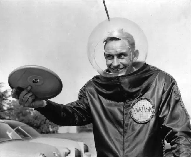 Fred Morrison dressed in a makeshift space suit holding a frisbee