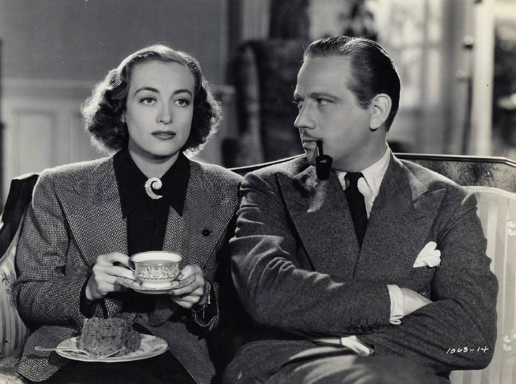 A young Joan Crawford (1938) drinking coffee from a teacup. She is wearing a spiral diamond brooch at her throat.