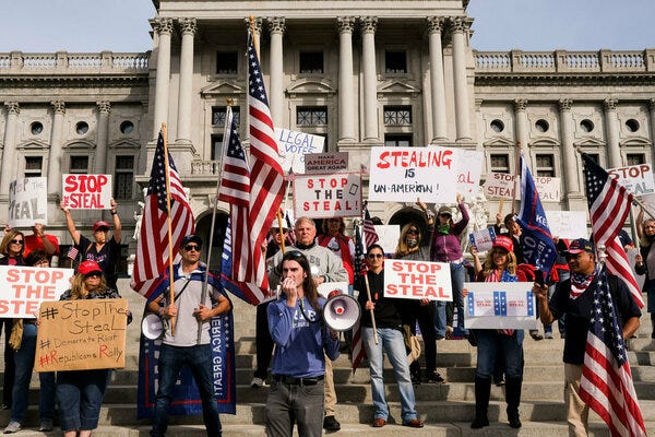 A group of supremacists wearing Trump flags and waving U.S. Flags stand on the steps of the U.S. Supreme Court and carry signs that read "Stop The Steal," indicating their support of the growing intent to establish dictatorial authoritarianism that they believe will favor them.