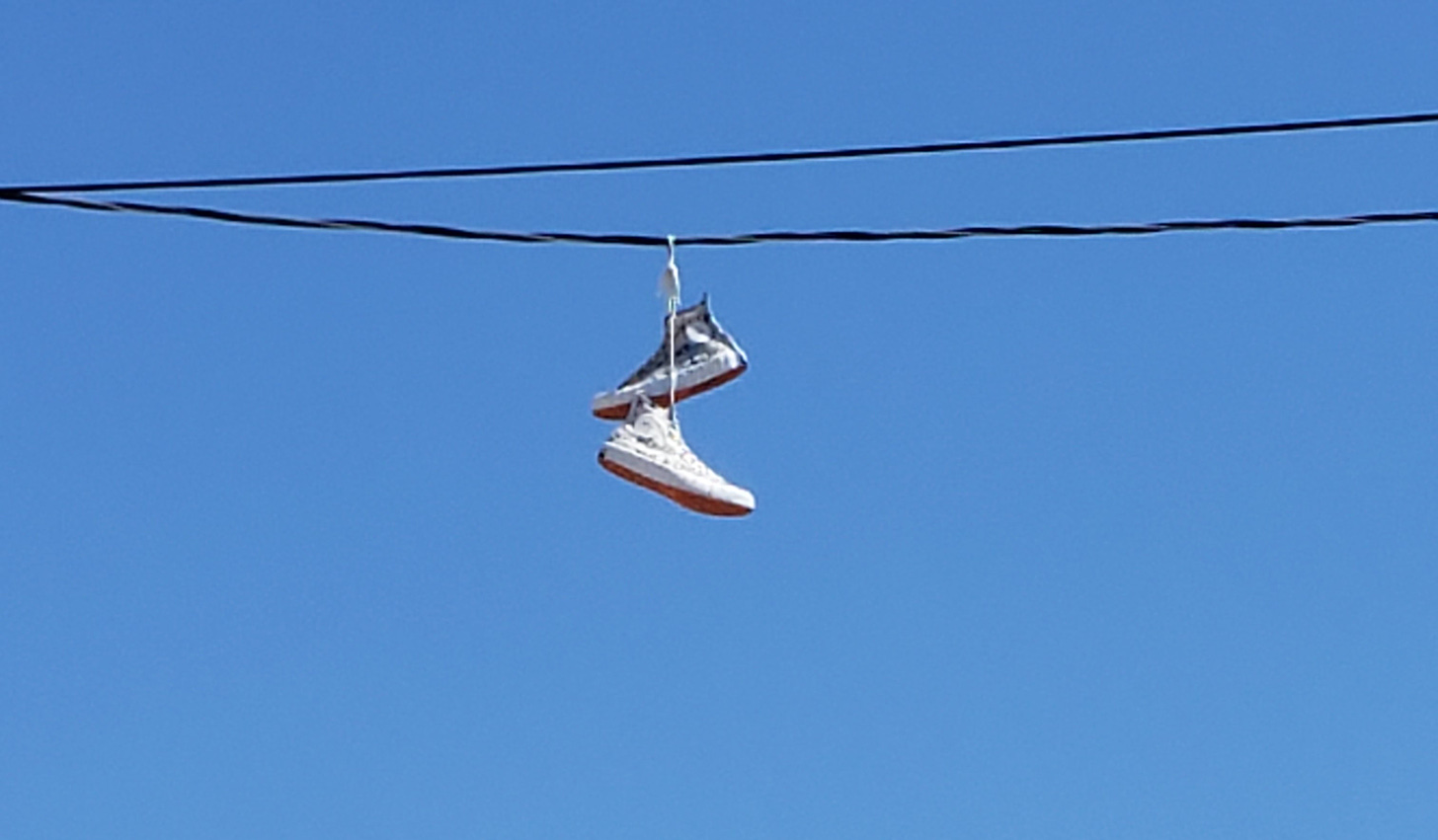 A pair of Converse sneakers hanging from electricity wires.