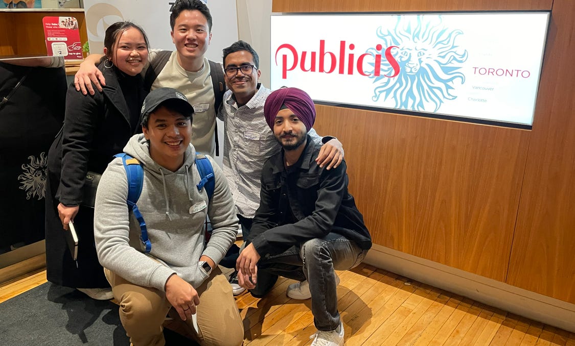 Four men and one woman posing indoors, in front of a banner for Publicis Toronto