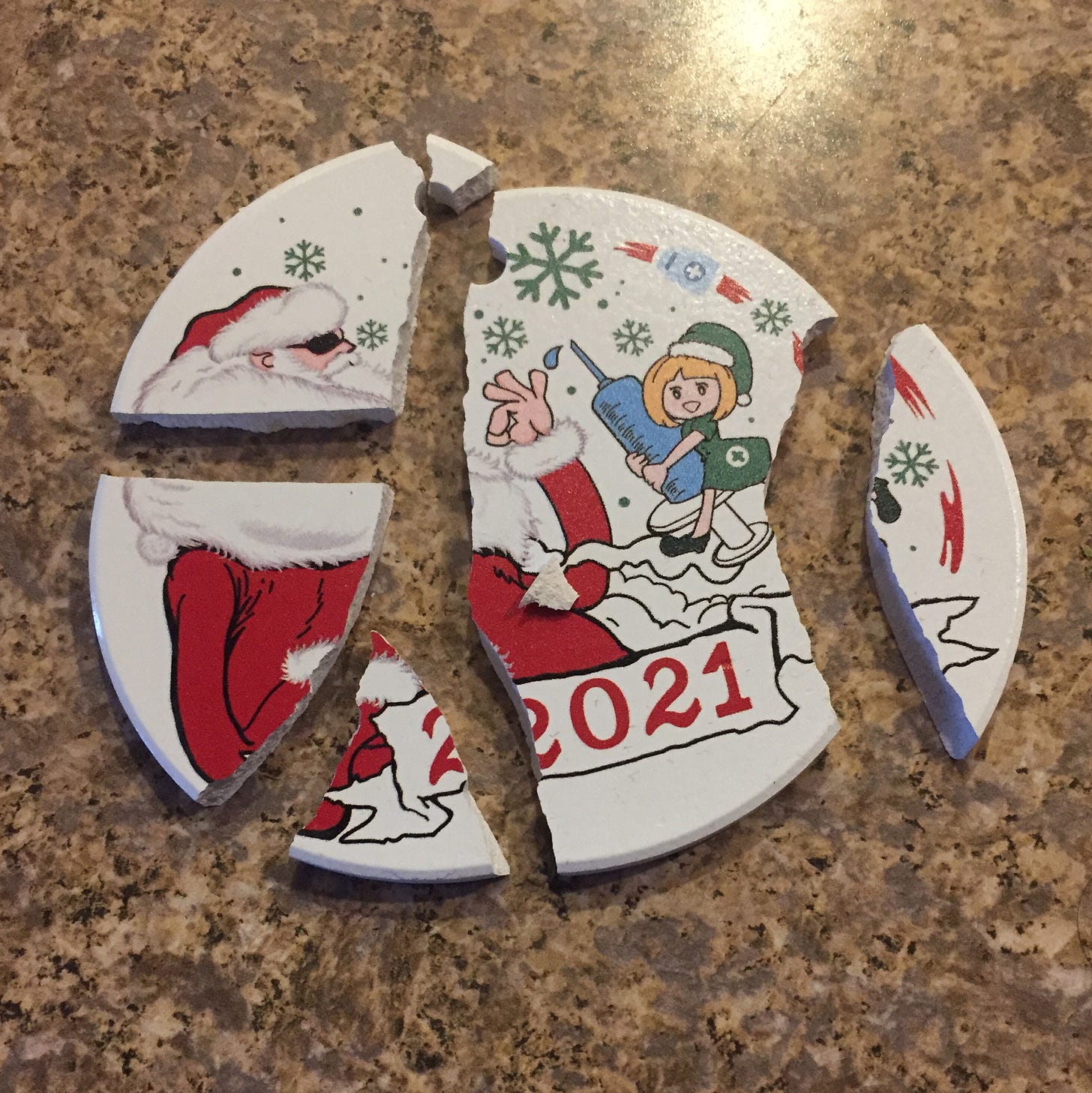 a broken Christmas ornament featuring a Santa wearing sunglasses, and a small elf holding a giant syringe. A banner at the bottom reads '2021'.
