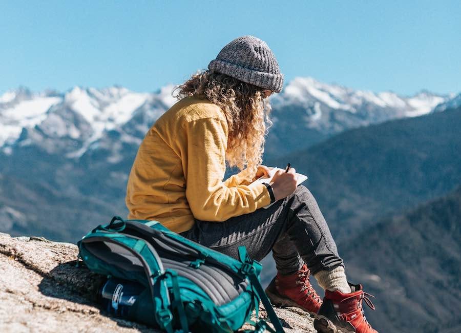 Woman writing in journal during mountain hike