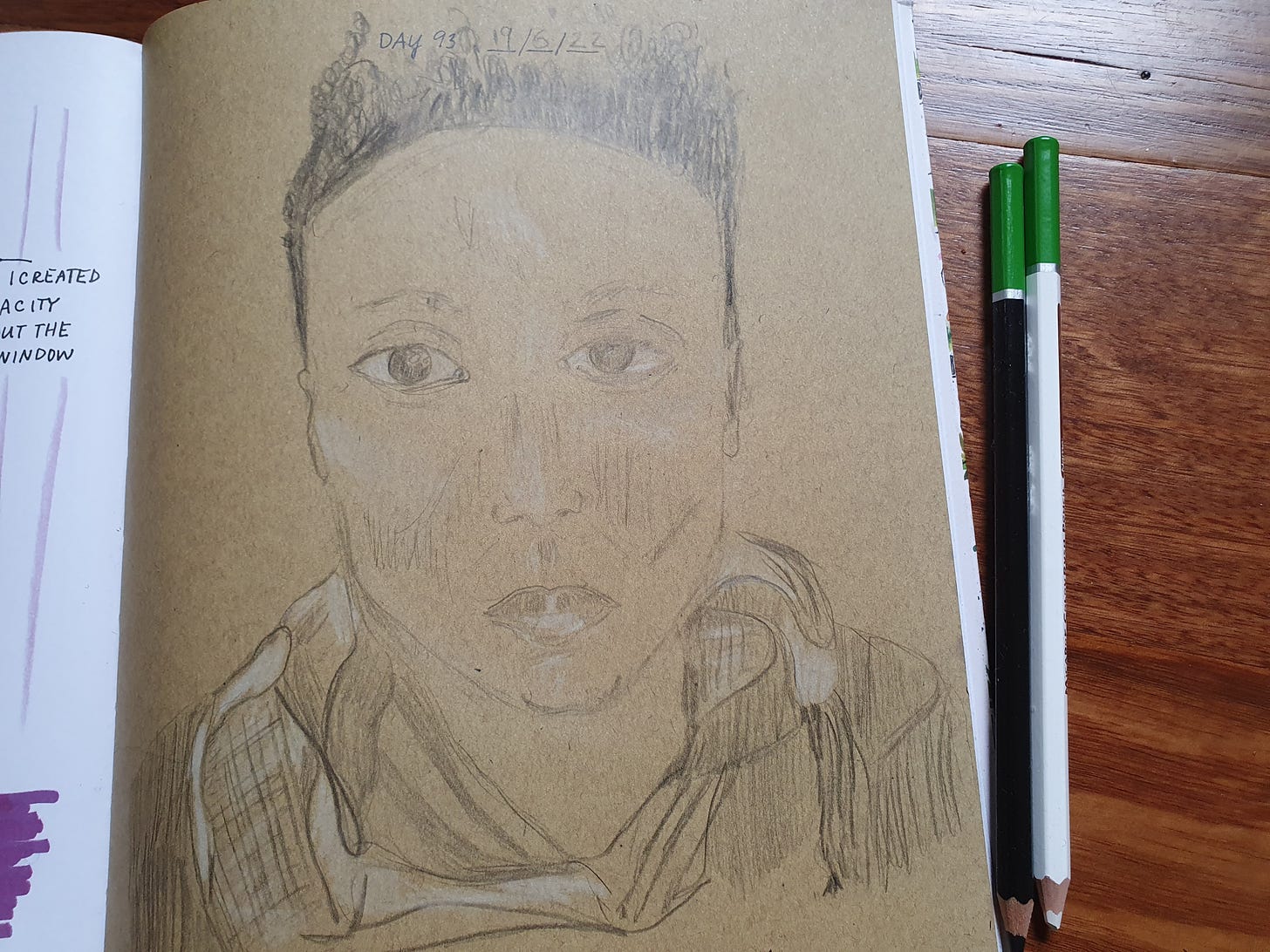 Photograph of a black and white pencil self portrait on brown paper.