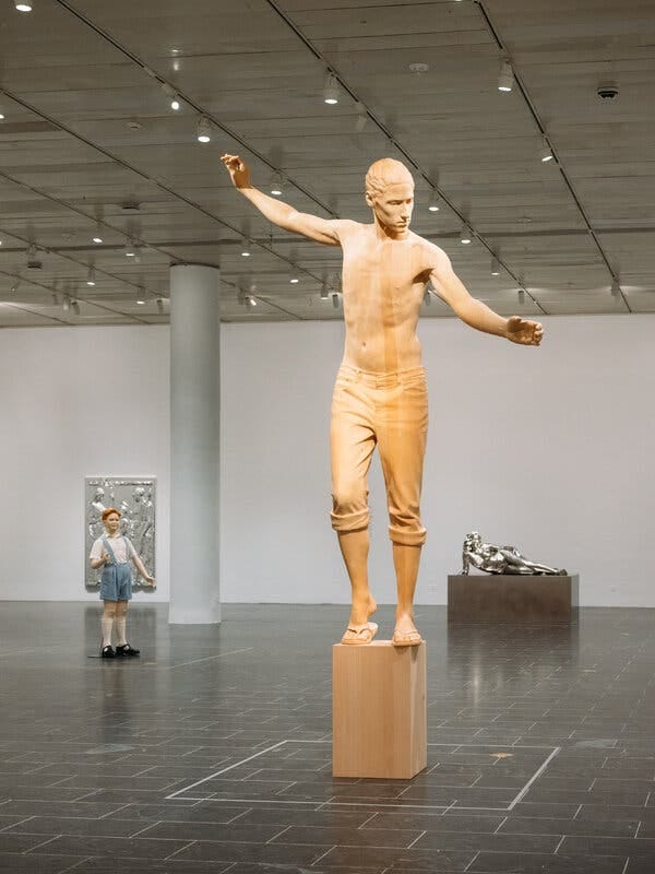 &ldquo;Archangel&rdquo; (2021), a new work in Japanese cypress by Charles Ray at the Met: a surfer-dude Gabriel alighting to Earth. Behind are &ldquo;Reclining Woman&rdquo; (2018), at right, and &ldquo;Boy&rdquo; (1992), left. His sculptures &mdash; classical and modern, universal and particular, grand and everyday &mdash; &ldquo;appear to slide through time itself.&rdquo;