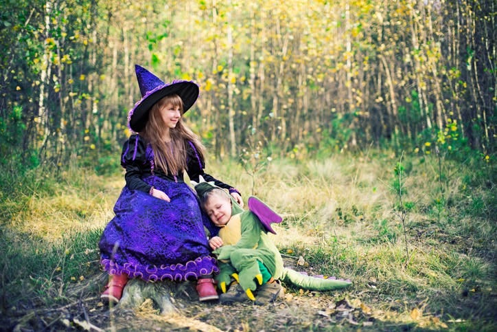 children in halloween costumes, one witch one dinosaur