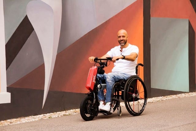 Male seated in a wheelchair using the Voi-branded Klaxon Klick device