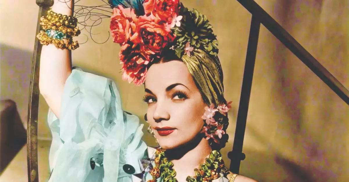 A picture of Brazilian actress and singer Carmen Miranda wearing a colorful jewelry and a turban full of flowers 