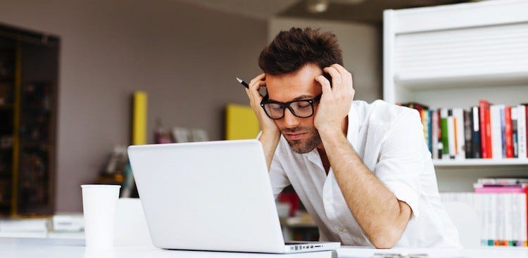 A stressed young man looking at a laptop