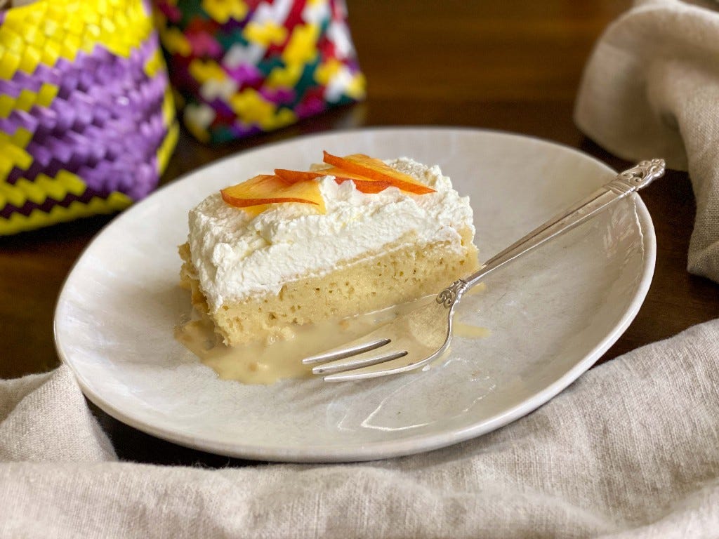 A slice of pastel de tres leches (tres leches cake) garnished with peach slices