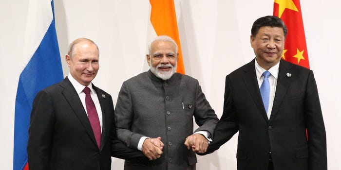 The leaders of India, Russia, and China holding hands and smiling