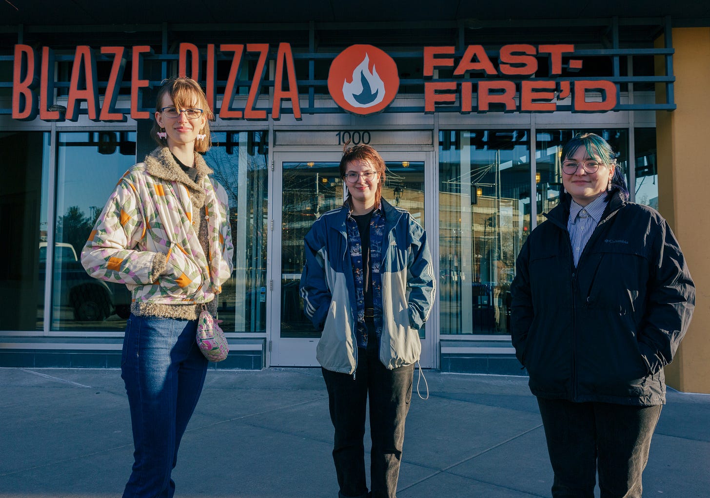 three people stand in front of the blaze pizza fast food store front wearing quilted and denim jackets