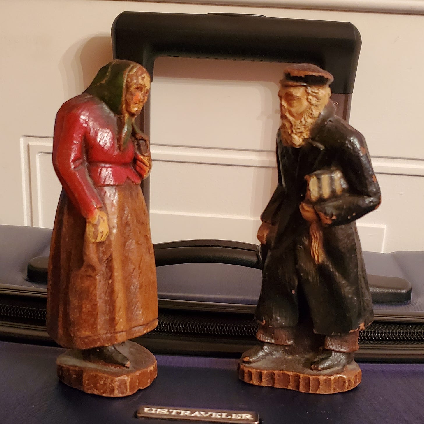 Figurines of an elderly Jewish couple in Eastern European dress perched on my suitcase.