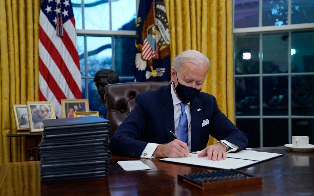 O presidente dos EUA, Joe Biden, assina seus primeiros atos executivos, no Salão Oval, na quarta-feira (20) — Foto: AP Photo/Evan Vucci