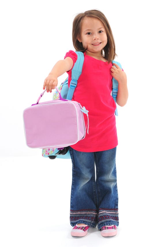Kindergarten girl holding lunchbox wearing backpack. - St. Peter Catholic  School