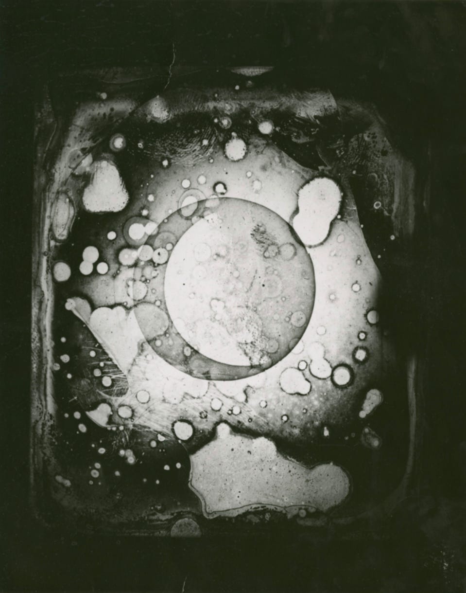 A round moon with a highlighted crescent can be seen on a damaged black-and-white daguerrotype. 