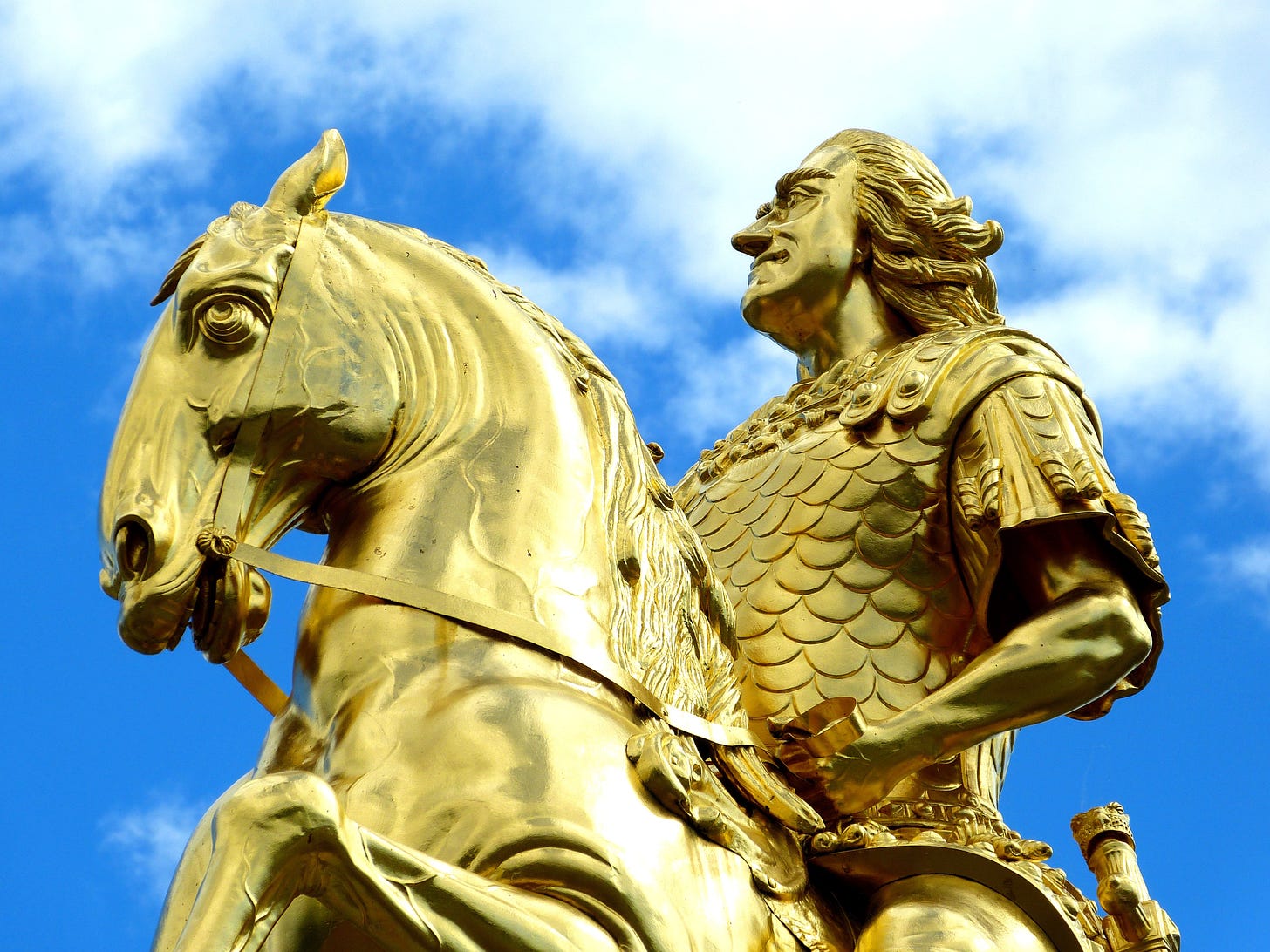 A golden statue of a king sitting on a horse.