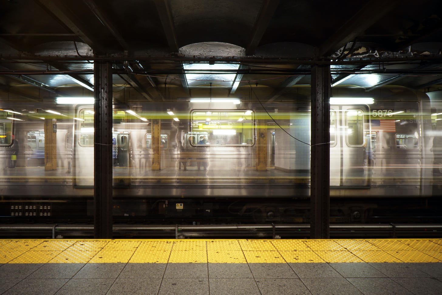 Photo of an underground subway platform, with blurring of train speeding by