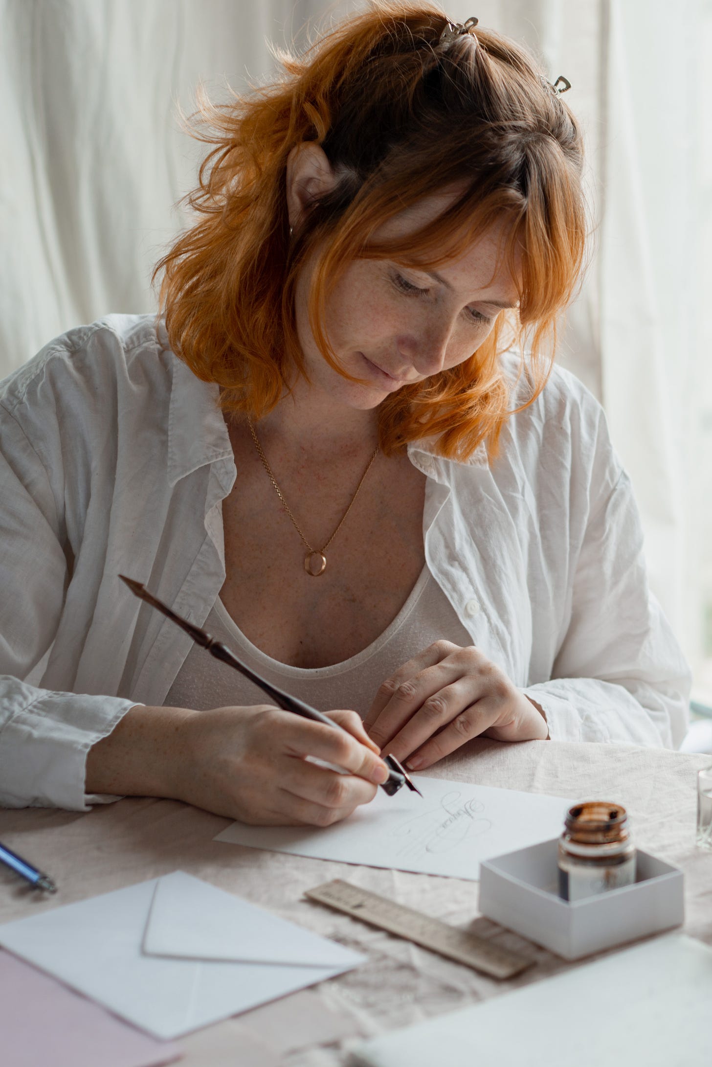 Red haired woman doing calligraphy on an envelope