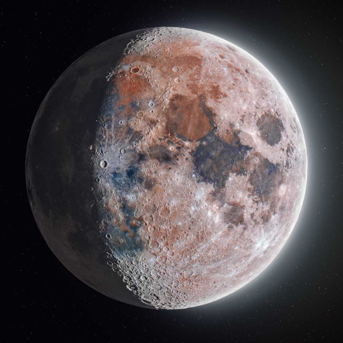 A close-up photo of Earth's moon, showcasing her craters and incredible variations in color, from peachy red tones to dark blue bruises, pinkish pale light and grey blemishes. The moon is in the waning gibbous phase.