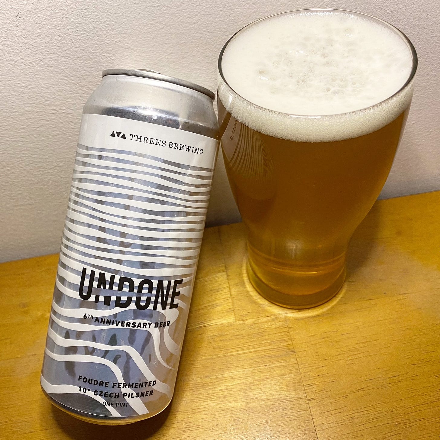 A photo of a can of Threes Brewing Undone, poured into a glass