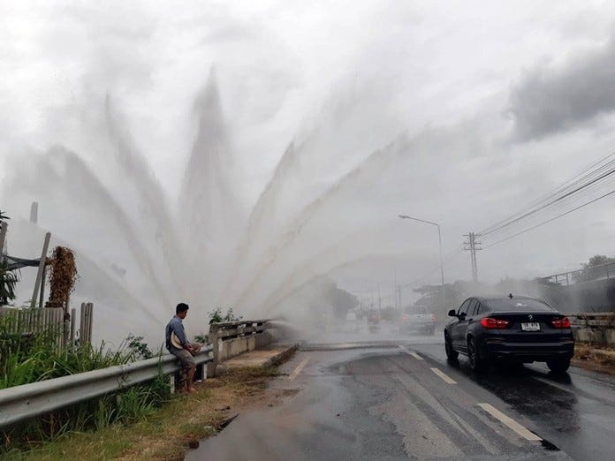 A local resident seems to be enjoying the 3-meter-high water fountain caused by a leaking large steel waterpipe along the railway road.