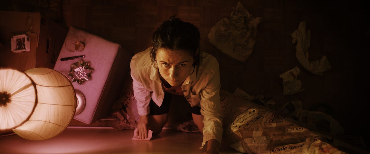 A woman staring up her wall, shot from above, bathed in light from her bedside table lamp as she looks worried