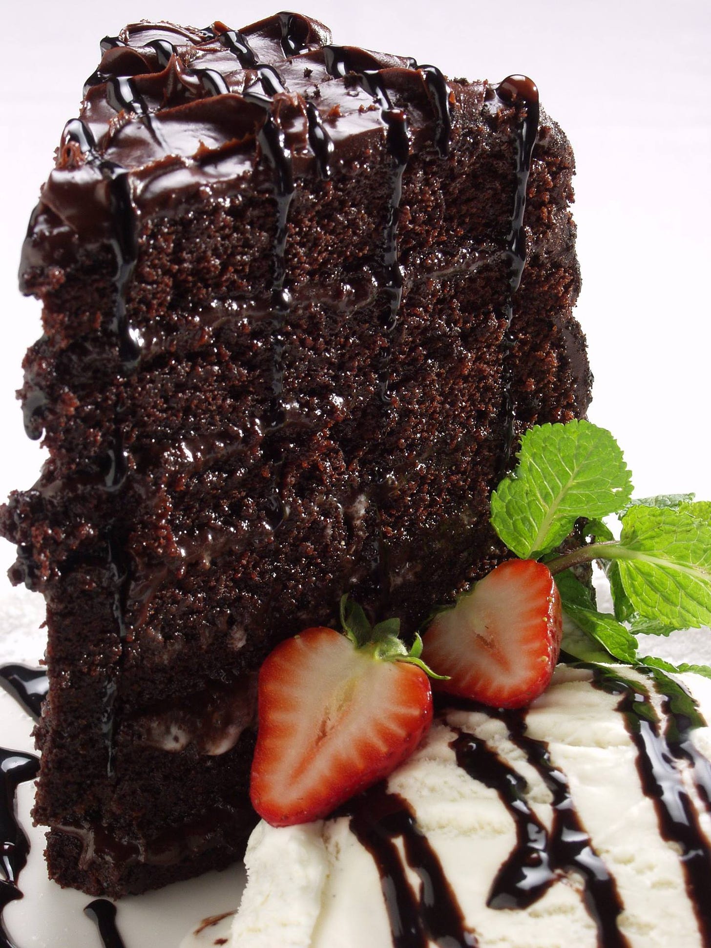 A very yummy piece of chocolate cake, ice cream and strawberries.