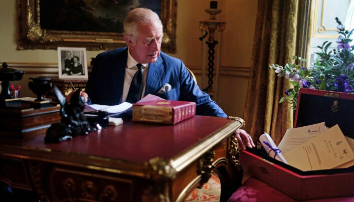 King Charles III carrying out official government duties from his red box in the Eighteenth Century Room at Buckingham Palace, London.